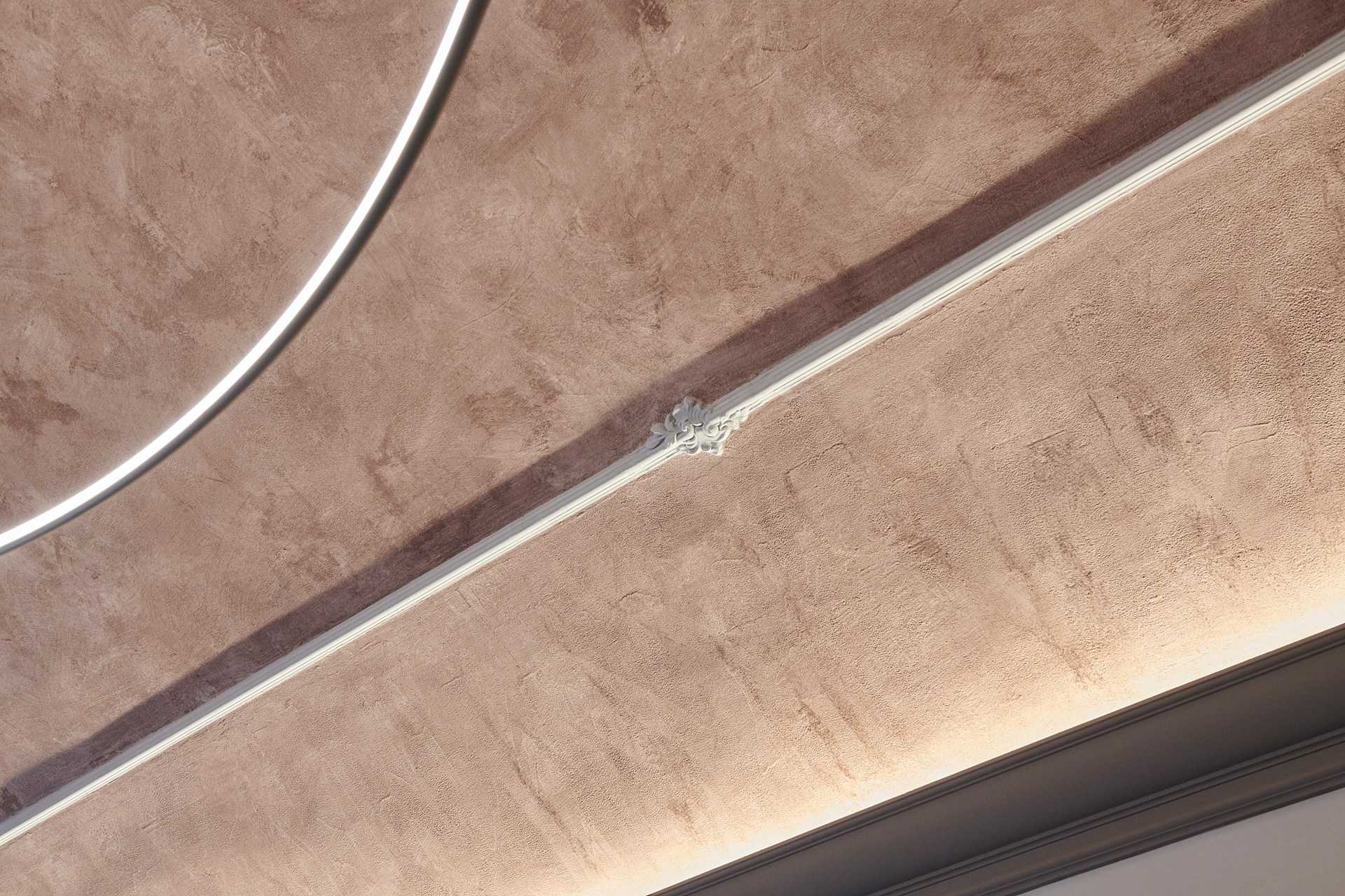 Una guardasilla decorativa que resalta las proporciones de la pared y realza el techo texturizado con iluminación integrada.